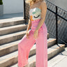 Full body view of model wearing the Pretty in Pink Pants that have pink fabric, a hidden front zipper with a hook closure, belt loops, an elastic waistband in the back, pockets on each side, and wide legs