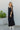 Full body front view of model wearing the Lennon Maxi Dress that has black flowy fabric, a two tiered body style, maxi length, black lining, a square neckline with ruffle trim, and tie straps.