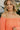 Upper front view of model wearing the Take Me To The Tropics Romper that has coral fabric, an elastic waist, a tie around the waist, an off-the-shoulder neck, and 3/4 flare sleeves with ruffle trim.