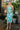 Full body front view of model wearing the Wanderlust Floral Midi Dress that has green, lavender and orange fabric with a floral pattern, midi length, a square neckline,  and adjustable straps.