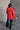 Full body back view of model wearing the Julianna Red Satin Long Sleeve Top that has red satin fabric, a high-low hem, a chest pocket, a notched collar neck, and long sleeves with buttoned cuffs.