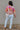 Full body back view of model wearing the Mila Pink Multi Long Sleeve Sweater which features orange, peach, cream and fuschia knit fabric, an upper floral print, ribbed hem, a ribbed round neckline, dropped shoulders, and long sleeves with ribbed cuffs.