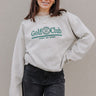 Front view of model wearing the Golf Club Beige & Green Sweatshirt which features beige knit fabric, a round neckline, and long sleeves with ribbed cuffs. Embroidered graphic says "Golf Club" "Sports Spa Resort" with golf clubs symbol in green threading.