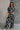 Full body front view of model wearing the Genevieve Black & Cream Printed Short Sleeve Top that has black fabric with a cream aztec pattern, a cropped waist, bubble hem, round neckline, a back key hole with a button, and short sleeves.