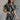 Front view of model wearing the Genevieve Black & Cream Printed Short Sleeve Top that has black fabric with a cream aztec pattern, a cropped waist, bubble hem, round neckline, a back key hole with a button, and short sleeves.