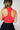 Back view of model wearing the Jada Red Cropped Racerback Tank Top that has red knit fabric, a cropped waist, built-in padding, a v-neckline with a collar, and a sleeveless design.