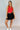 Full body front view of model wearing the Jada Red Cropped Racerback Tank Top that has red knit fabric, a cropped waist, built-in padding, a v-neckline with a collar, and a sleeveless design.