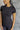 Close front view of model wearing the Robin Black Athletic Short Sleeve Top that has black athleisure fabric, monochrome stitch details, a scooped neckline, and short sleeves.