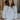 Front view of model wearing the Simply Yours Top that has ivory fabric with tan stitched stripes, a high-low hem, a notched neck with a tie and 3/4 sleeves