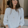 Front view of model wearing the Simply Yours Top that has ivory fabric with tan stitched stripes, a high-low hem, a notched neck with a tie and 3/4 sleeves