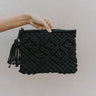 Front view of model holding the Get Away Clutch which features black cross stitched and tassel zipper.