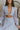 Close up view of model wearing the Enchanted Times Dress which features light blue and light purple fabric with purple embroidered flowers, a lining, a mini-length hem, a cutout in the mid section, a plunge neckline, a back zipper, and sheer balloon sleev