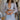 Front view of model wearing the Enchanted Times Dress which features light blue and light purple fabric with purple embroidered flowers, a lining, a mini-length hem, a cutout in the mid section, a plunge neckline, a back zipper, and sheer balloon sleev