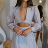 Front view of model wearing the Enchanted Times Dress which features light blue and light purple fabric with purple embroidered flowers, a lining, a mini-length hem, a cutout in the mid section, a plunge neckline, a back zipper, and sheer balloon sleev