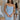 Front view of model wearing the Wishful Thinking Dress in Blue which features light blue fabric, mini length, overlap neckline with extra fabric, back sheer fabric with bands and gold zipper.