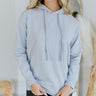 Front view of model wearing the Sunday Afternoon Sweatshirt that has light blue fabric, a high neckline with drawstrings and a hood, a thick hem, and long sleeves with cuffs.