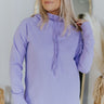 Close up view of model wearing the Lavender Haze Sweatshirt which features light purple fabric, a high-low hem, a high neckline, a hood with drawstrings, and long sleeves.