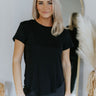 Front view of model wearing the Simply Made Top in Black which features black knit fabric, a round neckline, a scooped hem, and short sleeves with folded cuffs.