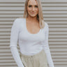 Front view of model wearing the You're A Classic Top in White which features white ribbed fabric, a scoop neckline, and long sleeves.