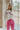 Front view of model wearing the Crazy In Love Sweater that has white knit fabric with a distressed hem, a round neckline,and  long sleeves The sweater says "Crazy in Love" in pink frill fabric
