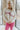 Front view of model wearing the Crazy In Love Sweater that has white knit fabric with a distressed hem, a round neckline,and  long sleeves The sweater says "Crazy in Love" in pink frill fabric