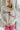 Front view of model wearing the Crazy In Love Sweater that has white knit fabric with a distressed hem, a round neckline,and  long sleeves The sweater says "Crazy in Love" in pink frill fabric