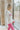 Side view of model wearing the Crazy In Love Sweater that has white knit fabric with a distressed hem, a round neckline,and  long sleeves The sweater says "Crazy in Love" in pink frill fabric