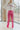 Front view of model wearing the Think Pink Pants that have pink fabric, a front zipper and hook closure, and flared legs