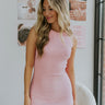 Front view of model wearing the You're A Keeper Dress that has light pink ribbed fabric, a mini-length hem, a halter neck, and a sleeveless body.