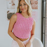 Front view of model wearing the Crushing On You Top which features pink bubble fabric, a cropped waist, a round neckline, a back keyhole with button a closure, and a sleeveless body.