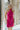 Front view of model wearing the Midnight Hour Dress which features fuchsia satin fabric, a mini-length hem, a halter neck with a back tie, an open back and sleeveless body.