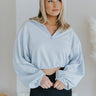Front view of model wearing the The Emerson Quarter-Zip Pullover in Blue that has light blue knit fabric, a cropped waist with drawstrings, a quarter-zip, and long sleeves
