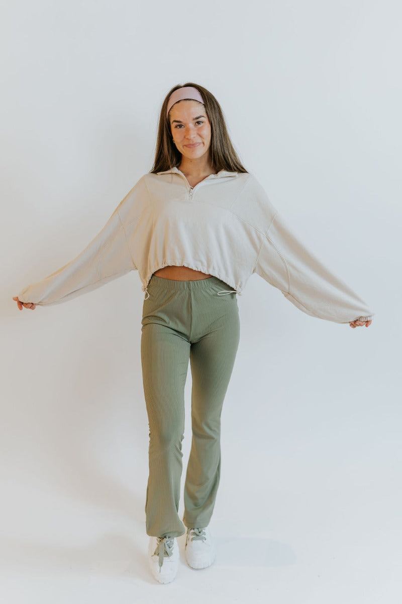 Full body front view of model wearing the Forget It Ribbed Pants that have olive green ribbed fabric, an elastic waistband, and flared legs.