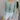Front view of model wearing the Give In To You Top which features green and light blue plisse fabric, skinny chevron fabric, lettuce hem, two front tie closures, collared neckline and long sleeves with lettuce hem.