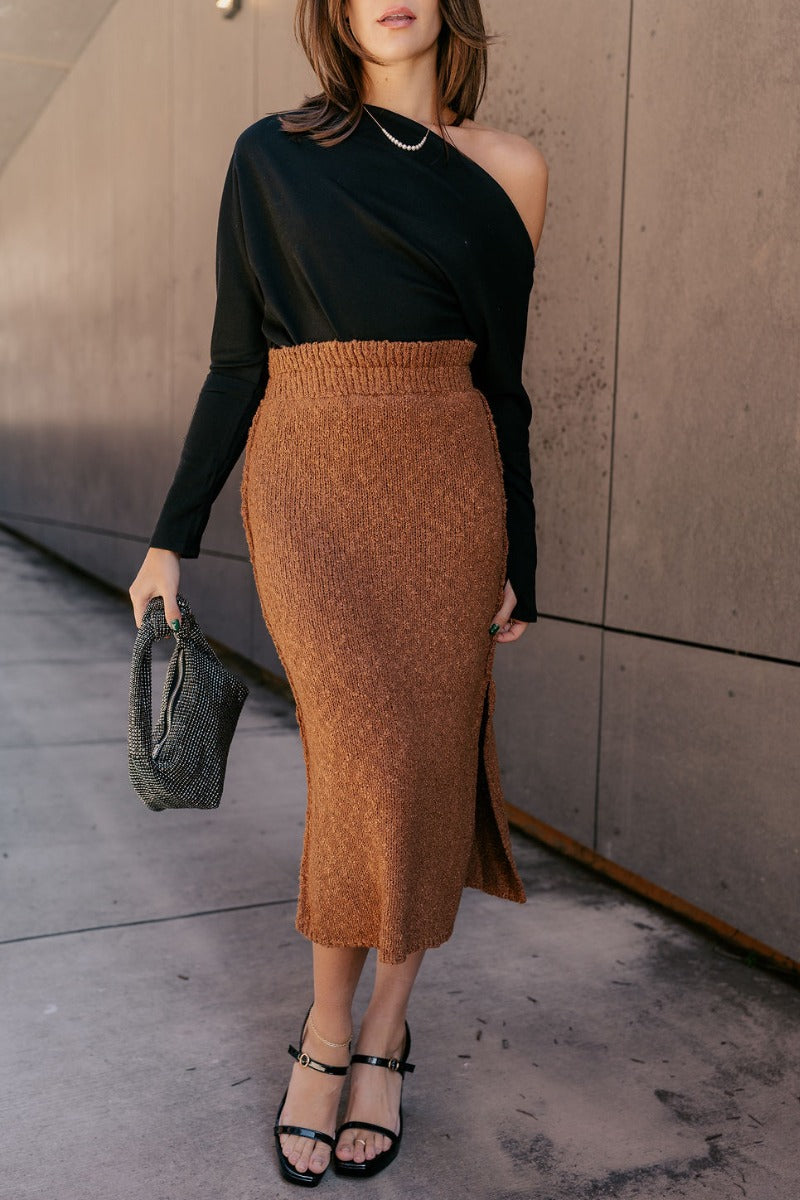 Front view of model wearing the Audrey Light Brown Textured Midi Skirt which features light brown textured knit fabric, midi length, a slit on the side, light brown thigh length lining, and an elastic waistband.