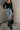 front view of model wearing the Jocelyn Denim Front Slit Midi Skirt that has medium-wash denim, midi length, pockets, a front slit, a front zipper, and belt loops.