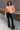 Full body view of model wearing the Nina Peach Cropped Long Sleeve Sweater which features peach knit fabric, a ribbed round neckline, dropped shoulders with exposed seams, and long flare sleeves.