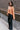 Side view of model wearing the Nina Peach Cropped Long Sleeve Sweater which features peach knit fabric, a ribbed round neckline, dropped shoulders with exposed seams, and long flare sleeves.