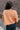 Back view of model wearing the Nina Peach Cropped Long Sleeve Sweater which features peach knit fabric, a ribbed round neckline, dropped shoulders with exposed seams, and long flare sleeves.