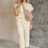 Full body front view of model wearing the Kalani Cream Quilted Pants that have cream fabric, a monochrome geometric quilted pattern, two front pockets, an elastic waist with a drawstring tie, and wide legs.