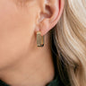 Side view of model wearing theStella Gold Rectangle Hoop Earrings that have small rectangle shaped gold hoops with grooves.