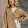 front view of model wearing the Kira Taupe Quilted Shacket that has taupe textured fabric with a quilted pattern, a left front chest pocket, a scooped hem, tortoise buttons, a collar, and long sleeves.