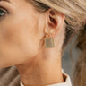 Side view of model wearing the Victoria Gold Rectangle Earrings that feature gold rectangles with dimensional shape designs.