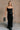 Full body front view of model wearing theElisa Black Satin Cowl Neck Maxi Dress that havs black satin fabric, maxi length,, a cowl neck, adjustable straps, and a back zipper with a hook closure.