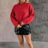 Full body front view of model wearing the Lorelei Red Mock Neck Sweater that has red cable knit fabric, ribbed hem, a high neck with braided details, dropped shoulders and long balloon sleeves.