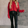 Full body view of model wearing the Amara Red Cable Knit Long Sleeve Sweater which features red knit fabric, monochrome cable knit design, ribbed hem, cropped waist, round neckline, dropped shoulders and long sleeves with cuffs.