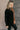Side view of model wearing the Freya Brown & Black Color Block Long Sleeve Sweater which features black and brown knit fabric, color-block pattern, high neckline, dropped shoulders and long sleeves with cuffs.