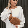 Front view of model wearing the Quinn Brown Sherpa Sling Bag that has brown sherpa fabric, an adjustable strap with black hardware, and a brown sherpa zip-up attachment.