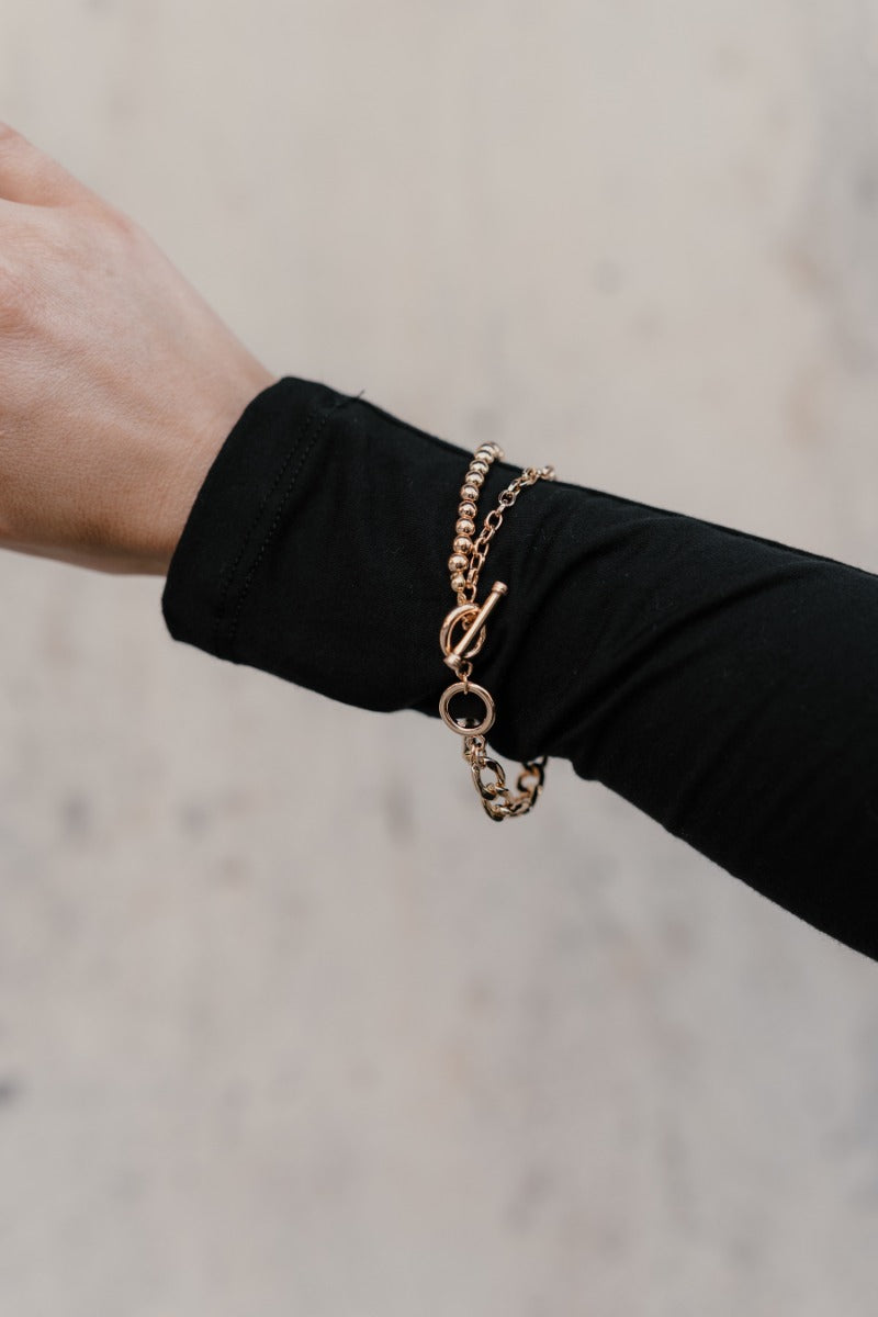 Image of model's wrist with the Lennon Gold Chain Toggle Bracelet that features one layer with gold beads and one layer with gold chain links joined togther by a toggle clasp.