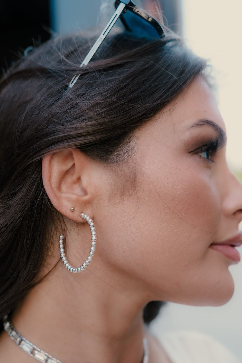 Side view of model wearing the Lila Silver Bead Hoop Earrings that feature open medium hoop with silver beads.
